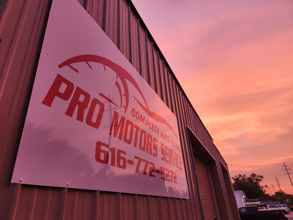 Springtime Suspension Check Pro Motors Service sign mounted on the shop building at sunset.