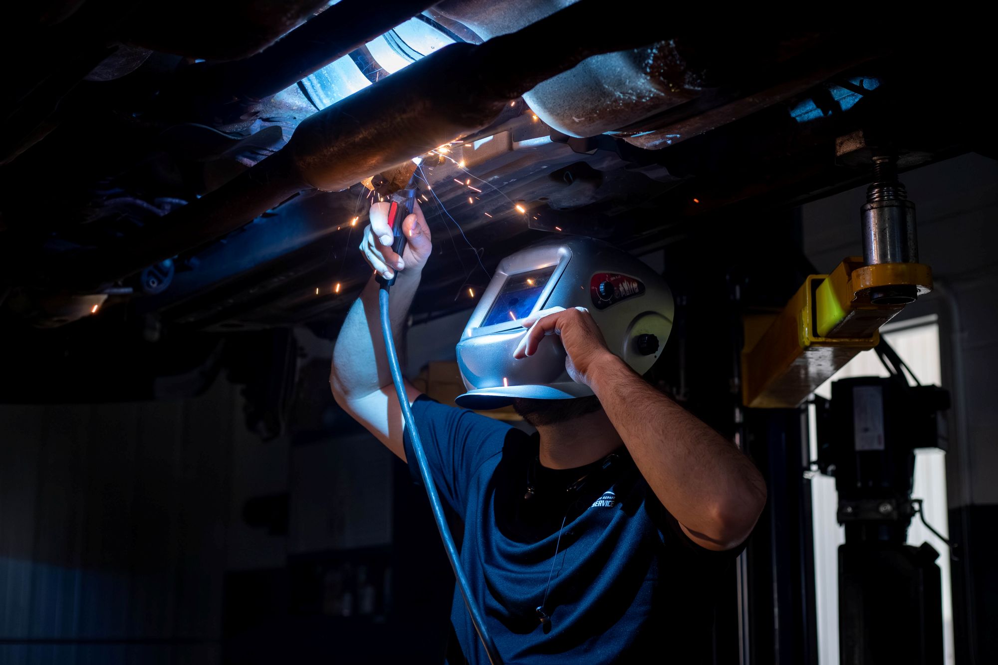 Tech Welding On Car Exhaust With Grey Welding Mask