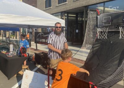 Pro Motors Service sign and basketball game booth at a Zeeland downtown street event.