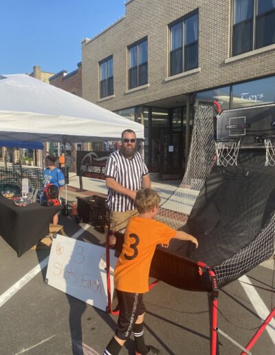 Pro Motors Service sign and basketball game booth at a Zeeland downtown street event.